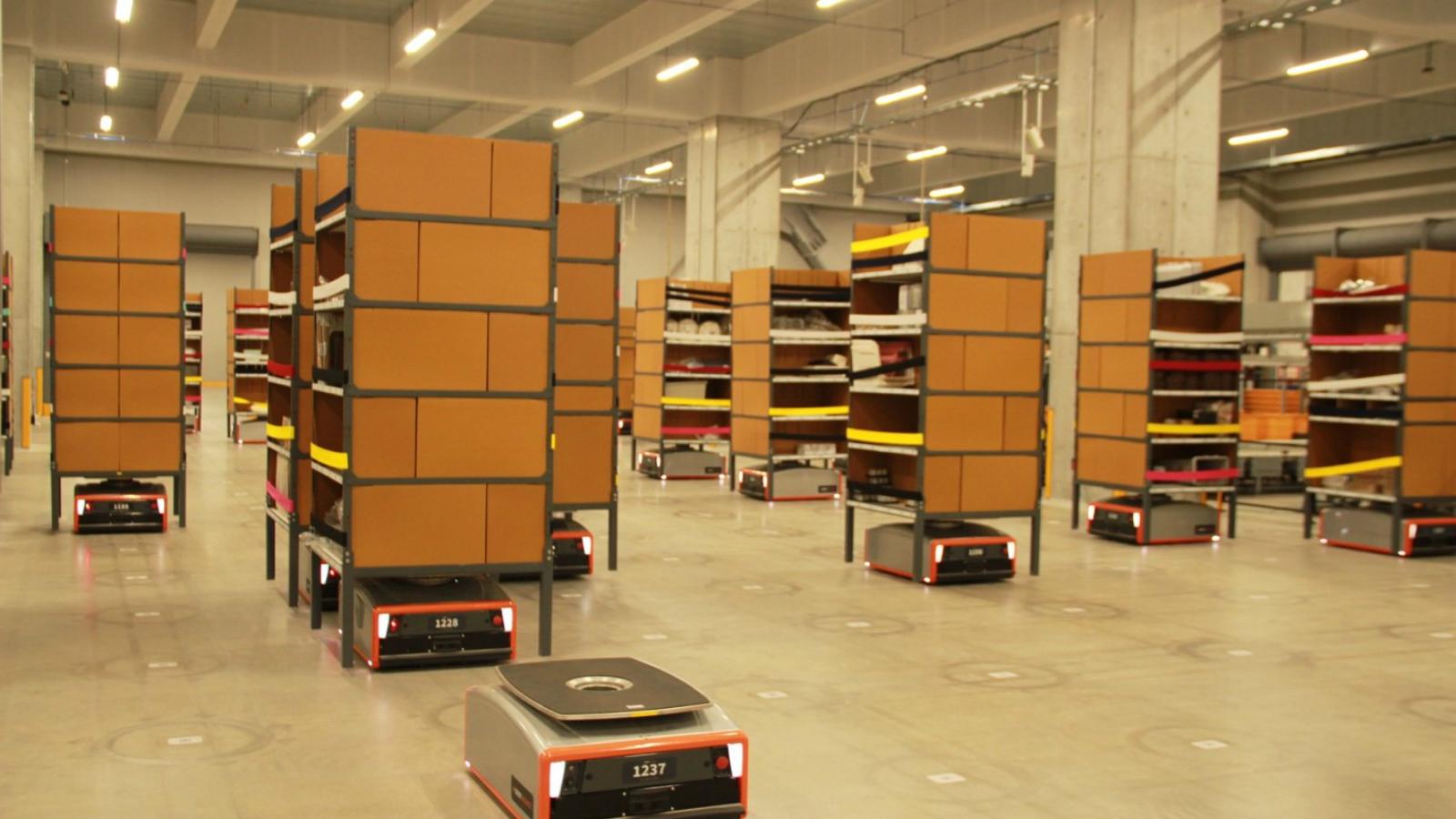 Robot mobili arancioni in un corridoio di magazzino automatizzato in stile Amazon